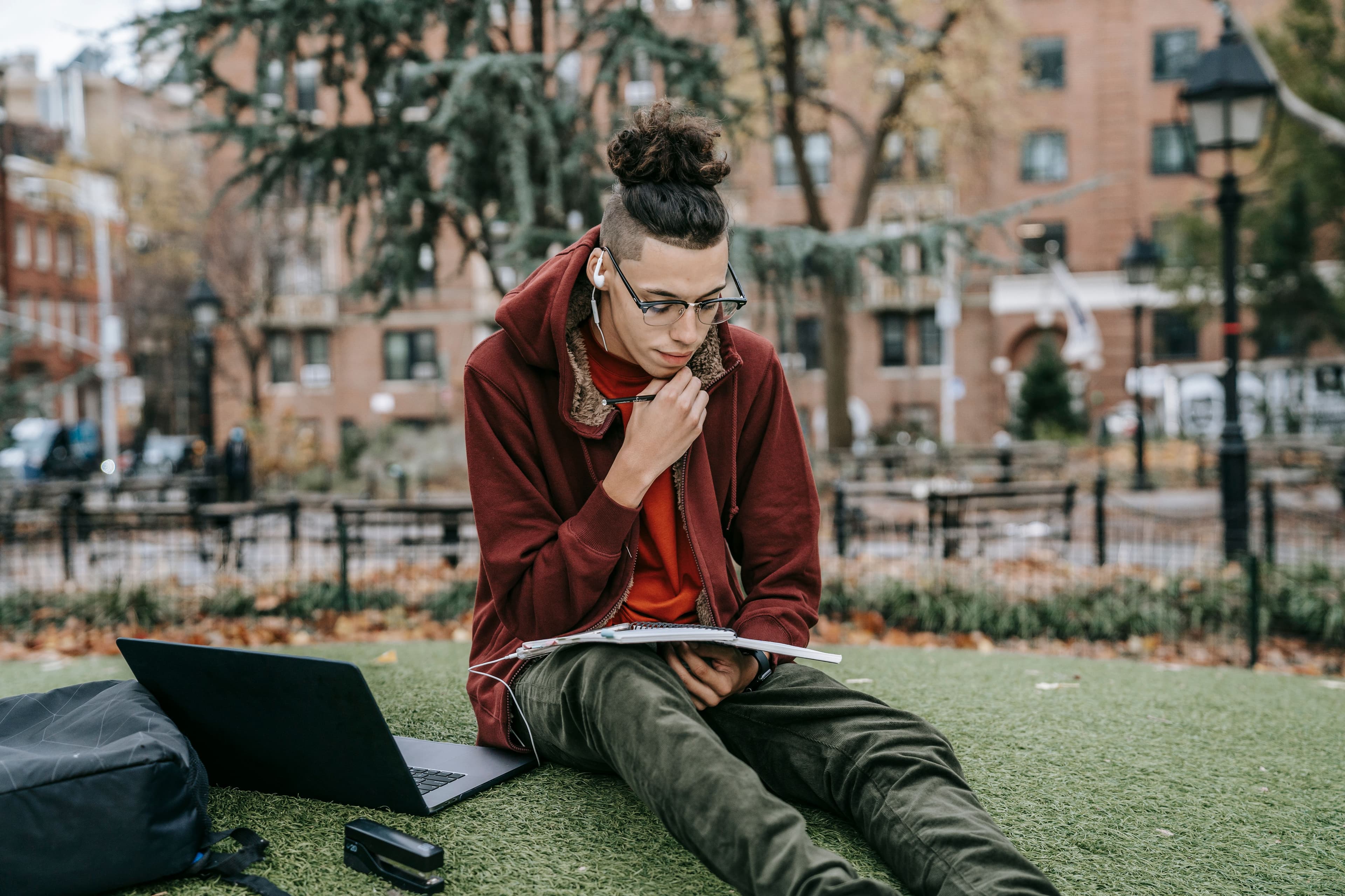Student studying with a laptop and notebook on a university campus